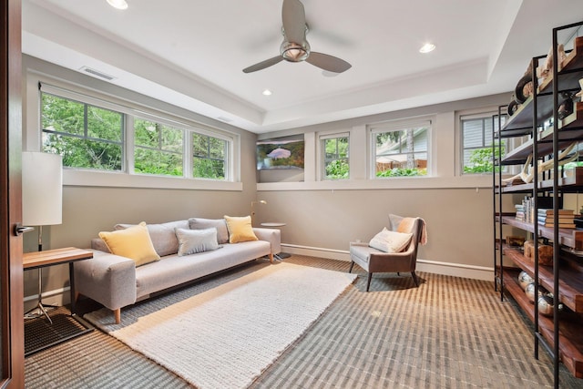living area with plenty of natural light, ceiling fan, baseboards, a raised ceiling, and recessed lighting