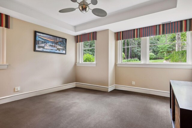 carpeted spare room featuring baseboards, a ceiling fan, and a tray ceiling