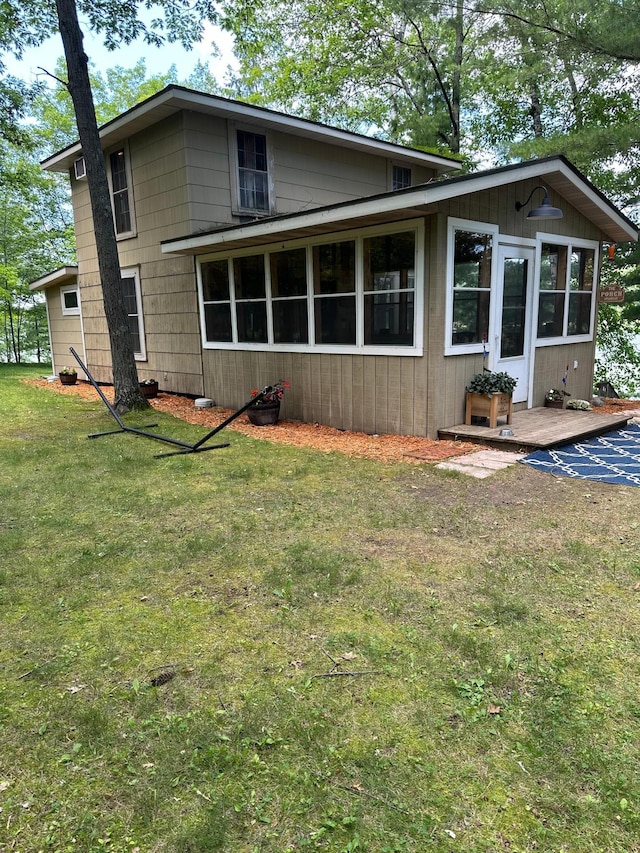 rear view of house featuring a sunroom and a yard