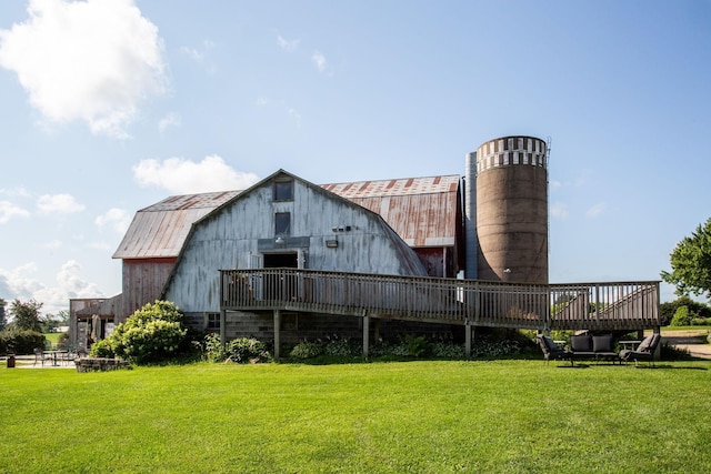 back of property with a deck, a lawn, and an outbuilding