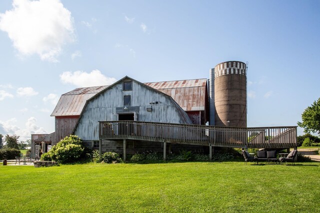 rear view of property featuring an outdoor structure, a wooden deck, and a lawn