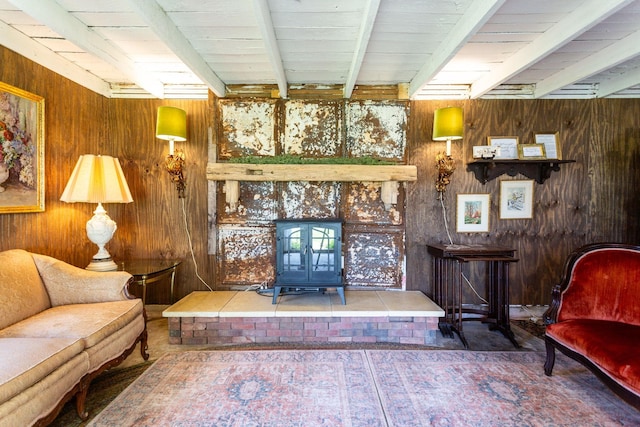 living area with a wood stove, beamed ceiling, and wooden walls