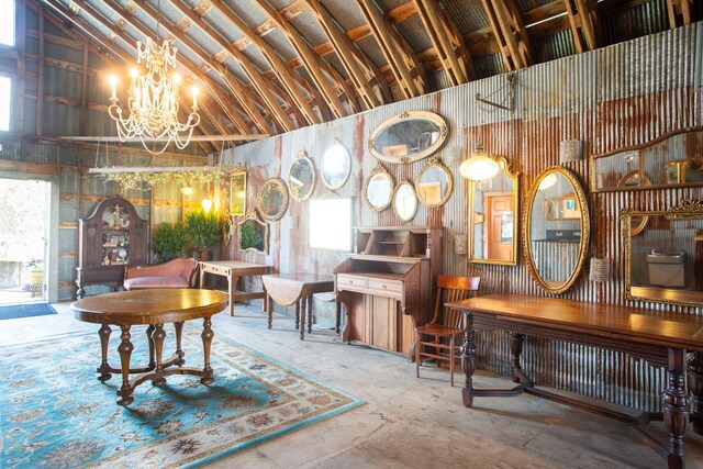 misc room with a wealth of natural light, a chandelier, concrete flooring, and high vaulted ceiling