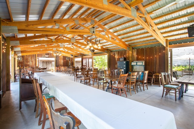 dining area with concrete floors, wood walls, and vaulted ceiling with beams