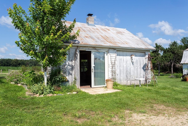 rear view of property with an outdoor structure and a lawn