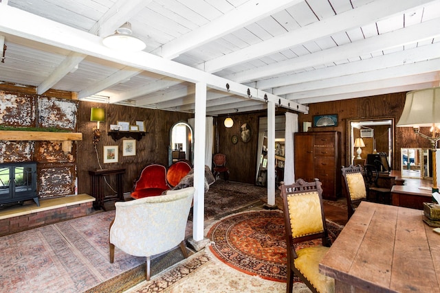 living room with a wood stove, wood walls, beam ceiling, and wood ceiling