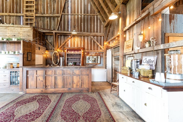 kitchen with hardwood / wood-style flooring, high vaulted ceiling, and wood walls