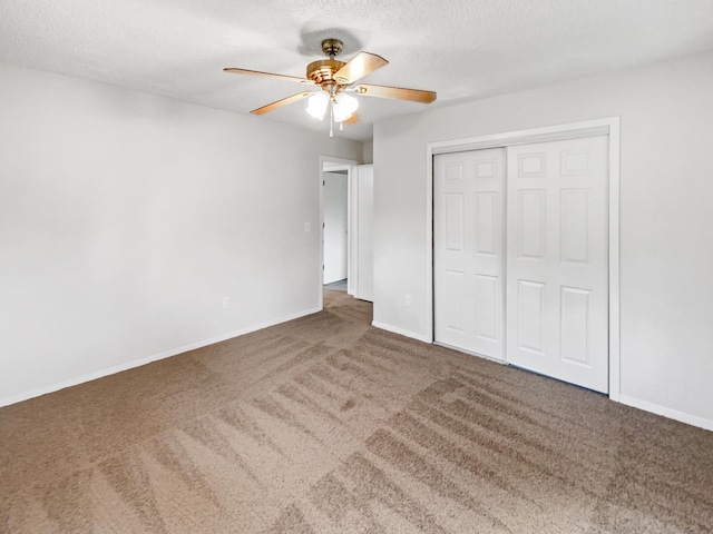 unfurnished bedroom featuring ceiling fan, a textured ceiling, a closet, and dark colored carpet