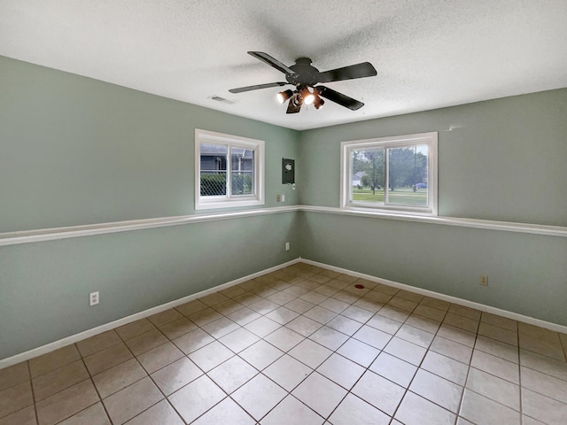 spare room with ceiling fan, light tile patterned flooring, and a textured ceiling