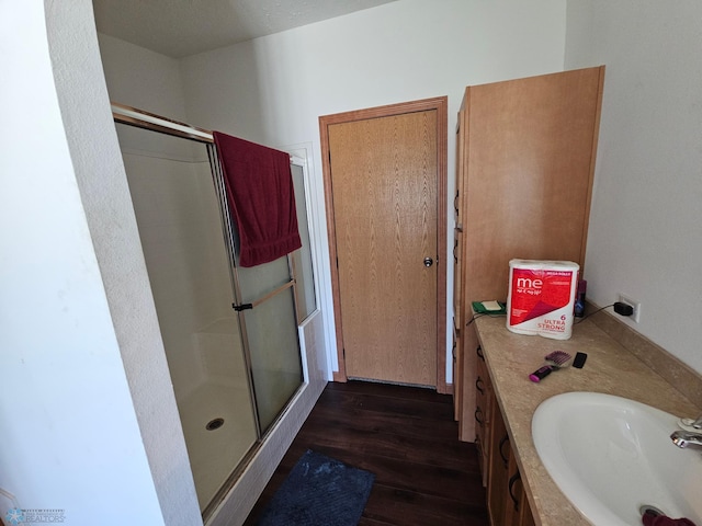 bathroom with a shower with shower door, vanity, and hardwood / wood-style flooring