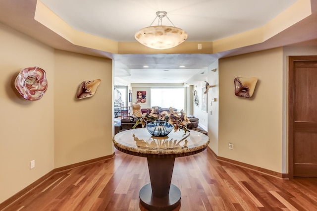 dining area featuring wood-type flooring and a raised ceiling