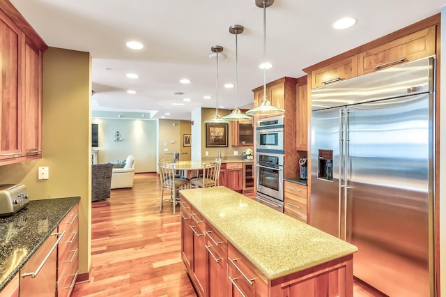 kitchen featuring a center island, light hardwood / wood-style floors, light stone countertops, and appliances with stainless steel finishes