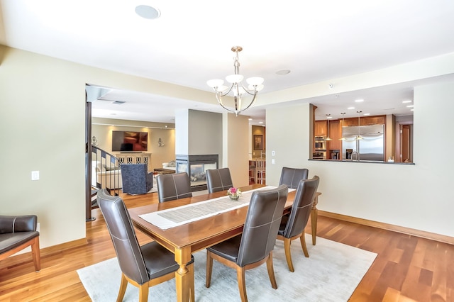 dining room featuring a chandelier, light hardwood / wood-style floors, and a multi sided fireplace