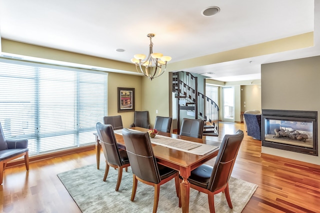 dining area featuring an inviting chandelier, a multi sided fireplace, and light hardwood / wood-style flooring