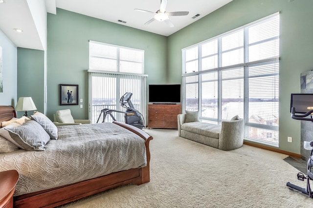 bedroom featuring a high ceiling, multiple windows, ceiling fan, and carpet flooring