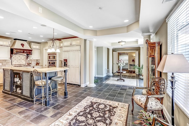 kitchen with built in appliances, premium range hood, decorative backsplash, and dark tile patterned floors