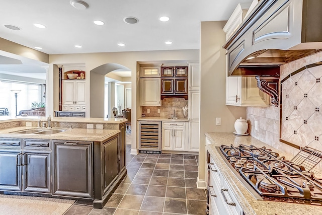 kitchen with dark tile patterned floors, sink, premium range hood, backsplash, and beverage cooler