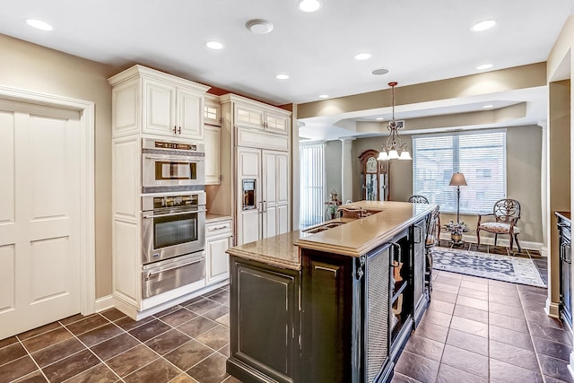 kitchen with a center island, double oven, dark tile patterned flooring, pendant lighting, and sink