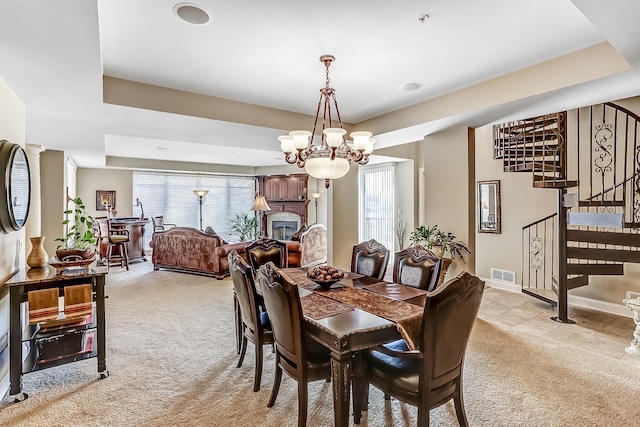 dining area with a chandelier, light carpet, and a tray ceiling