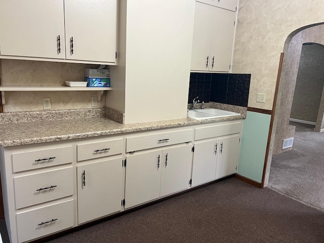 kitchen featuring white cabinetry, dark colored carpet, and sink