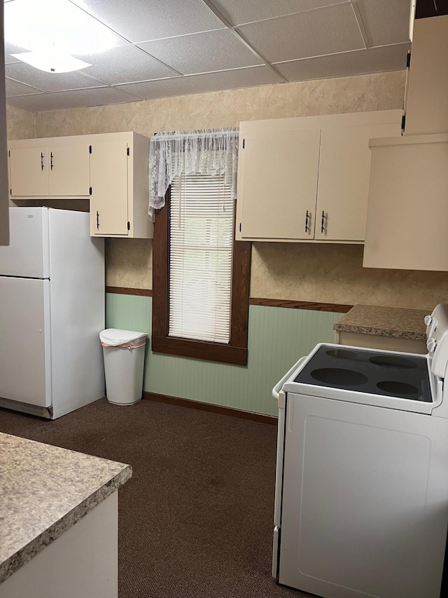 kitchen with carpet floors, white appliances, and a drop ceiling