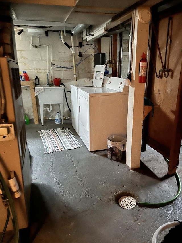 unfinished below grade area with washer and clothes dryer, concrete block wall, and a sink