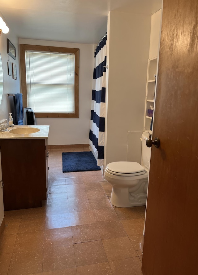 bathroom with toilet, baseboards, and vanity