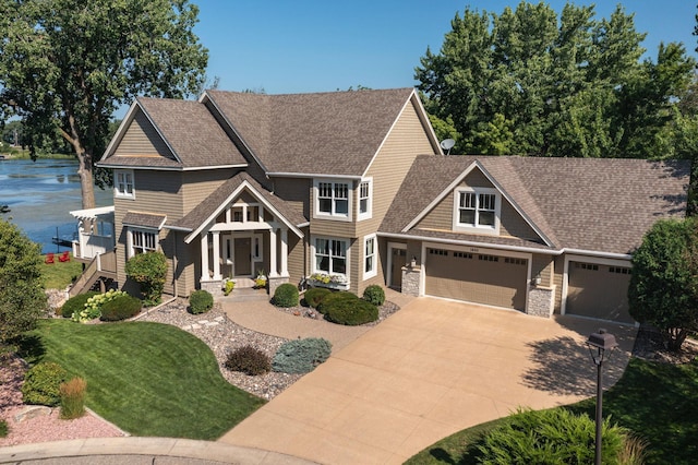 craftsman house featuring an attached garage, driveway, stone siding, roof with shingles, and a front yard