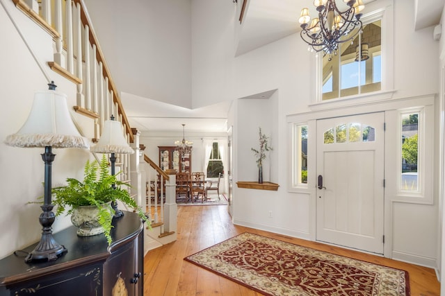 entryway featuring a chandelier, light wood-style flooring, a high ceiling, and stairs