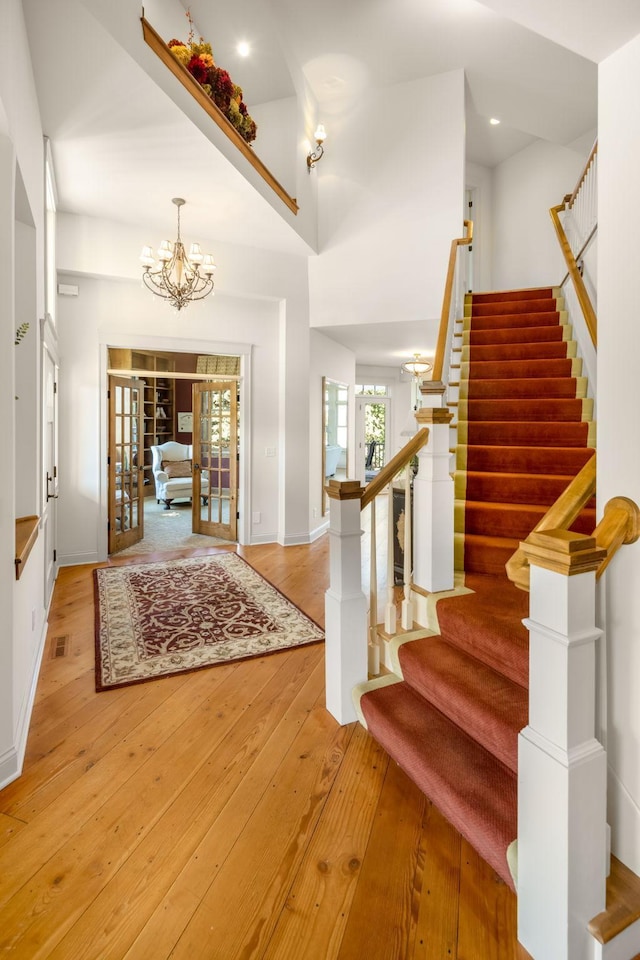 foyer featuring a chandelier, visible vents, stairs, french doors, and hardwood / wood-style floors