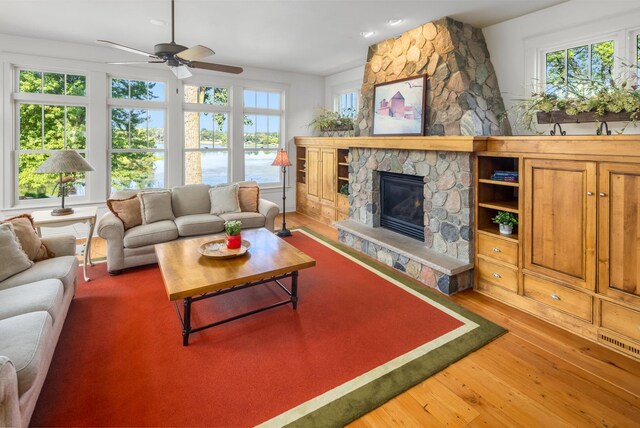 living room with a fireplace, plenty of natural light, wood-type flooring, and ceiling fan