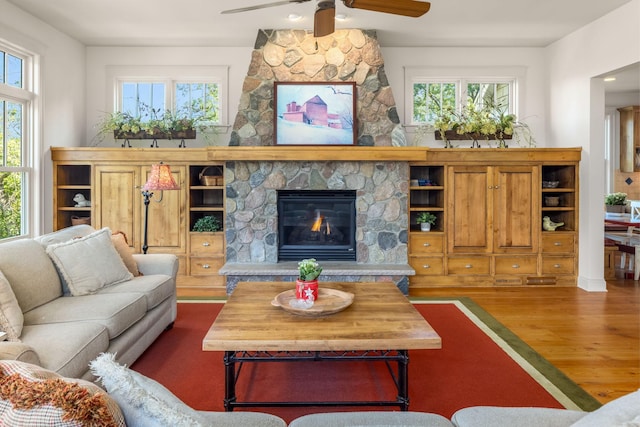 living area featuring ceiling fan, a fireplace, and wood finished floors