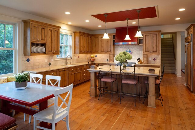 kitchen with a kitchen island, sink, tasteful backsplash, and light hardwood / wood-style flooring