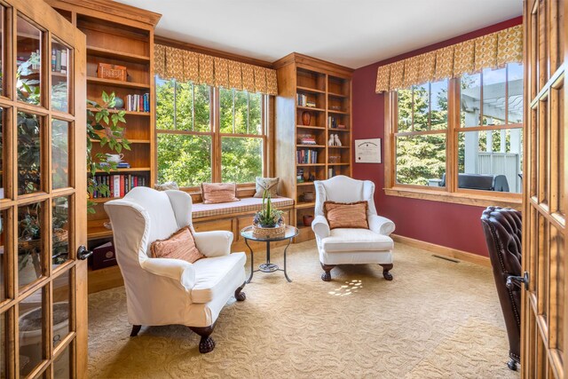 sitting room featuring built in features, plenty of natural light, and carpet