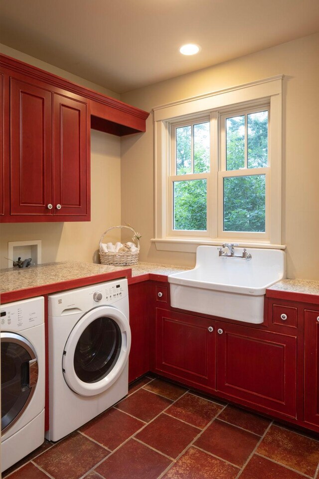 laundry room with washing machine and clothes dryer, cabinets, sink, and dark tile patterned flooring