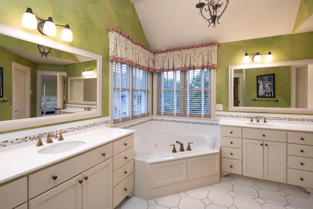 full bathroom with vaulted ceiling, a tub with jets, two vanities, and a sink