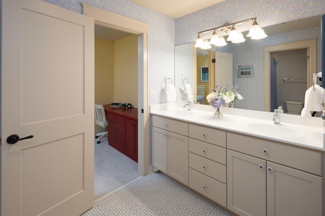 full bath with double vanity, a sink, and wallpapered walls