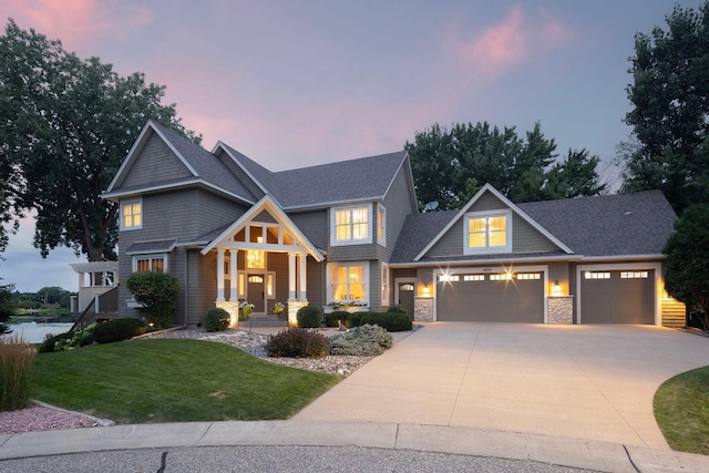 craftsman-style home with a shingled roof, a garage, stone siding, driveway, and a front lawn