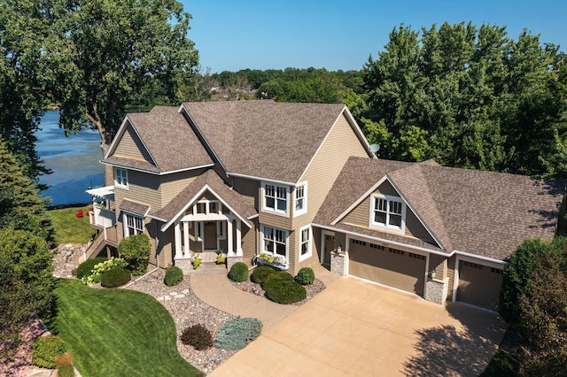 craftsman inspired home featuring a shingled roof, concrete driveway, and a front yard