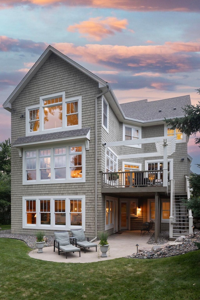 back house at dusk with an outdoor hangout area, a patio area, and a yard