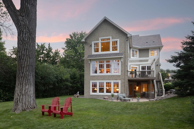 back of house at dusk with a patio, stairway, a wooden deck, and a lawn