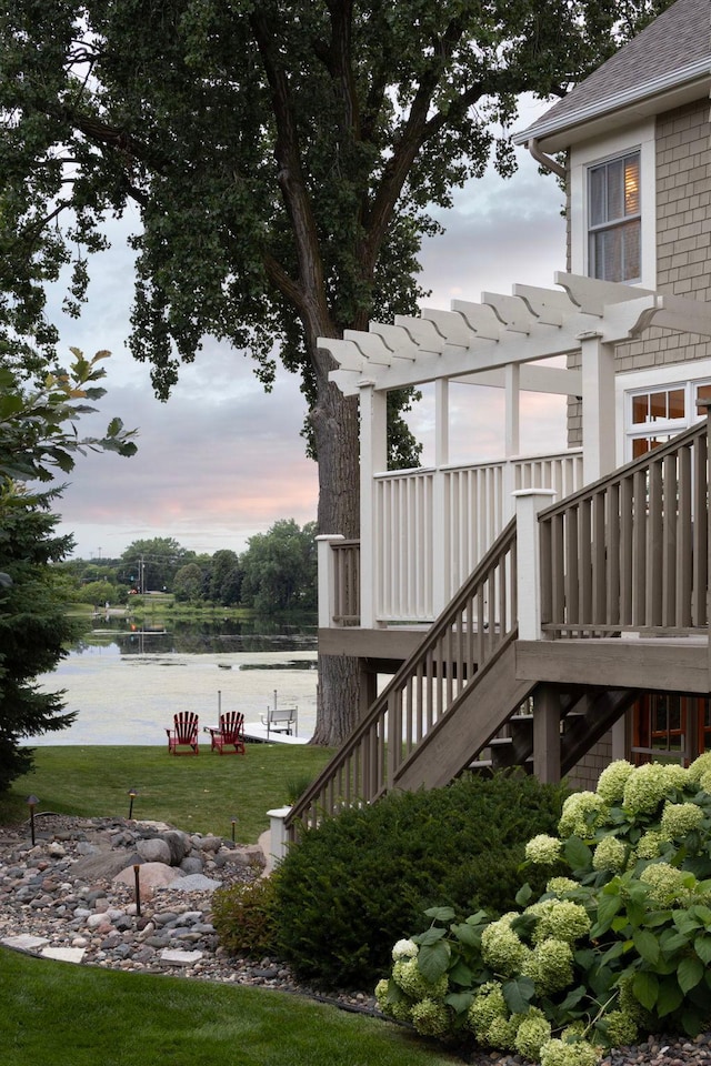 exterior space featuring stairs, a lawn, and a water view