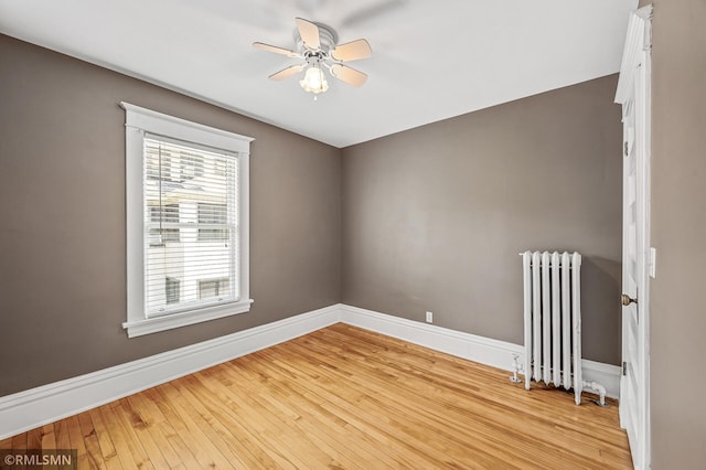 unfurnished room featuring radiator, light hardwood / wood-style flooring, and ceiling fan