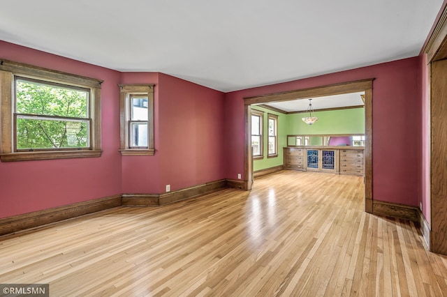 unfurnished living room featuring a healthy amount of sunlight, a chandelier, and light hardwood / wood-style floors