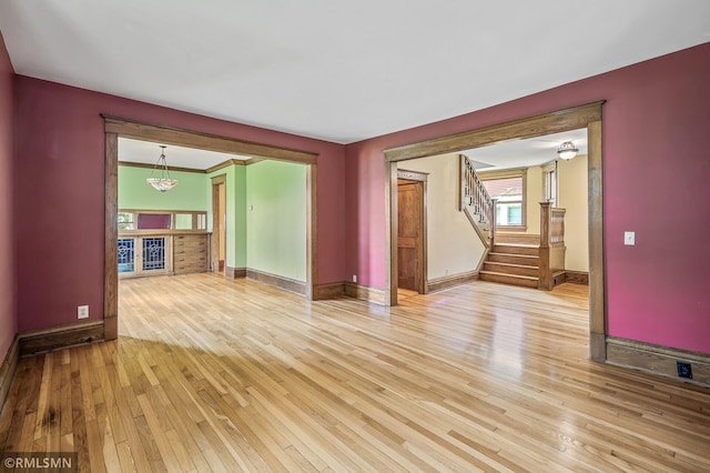 unfurnished living room with a notable chandelier and light wood-type flooring