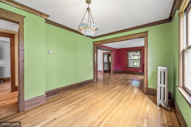 empty room featuring ornamental molding, radiator, and light wood-type flooring