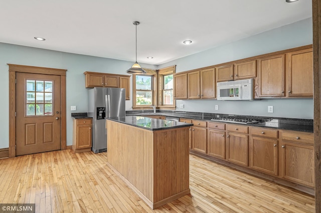 kitchen featuring pendant lighting, light hardwood / wood-style floors, appliances with stainless steel finishes, and a kitchen island