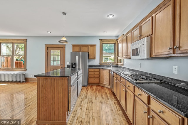 kitchen with stainless steel appliances, pendant lighting, light hardwood / wood-style floors, radiator, and a center island