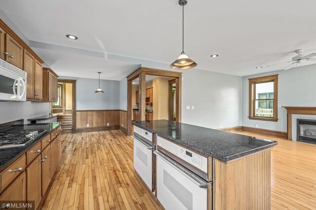 kitchen with a tiled fireplace, light hardwood / wood-style flooring, white appliances, and hanging light fixtures