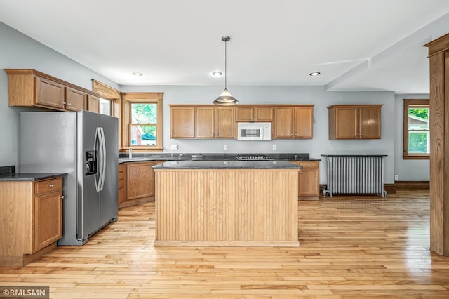 kitchen with a center island, a wealth of natural light, stainless steel fridge with ice dispenser, and light wood-type flooring